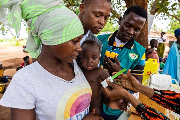 Photo of a mother and her child amidst health workers during a vaccination session in Mozambique.